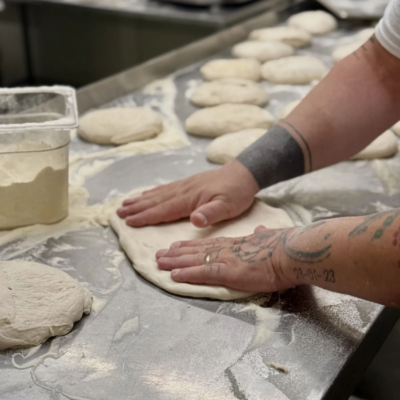 Ein Pizzaboden wird in unserer Manufaktur von Hand ausgebreitet